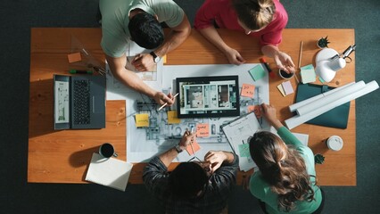 Top down view of civil engineers using tablet to design house structure while sitting at table with...
