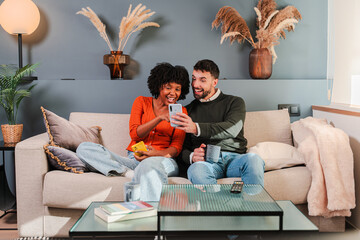 Happy couple enjoying a playful moment together as they share laughter while using their smartphone...