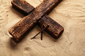 Wooden cross with nails on sand. Good Friday concept