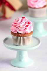 Stand with tasty cupcake for Valentine's Day on light background