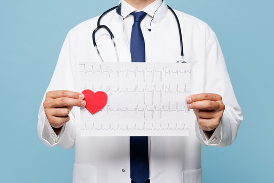 Fototapeta Close up young male doctor man wear white medical gown suit work in hospital clinic office hold electrocardiogram record, heart ekg cardiogram chart of wave in paper isolated on plain blue background.