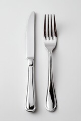 Close-up of modern cutlery: knife and fork with reflective metal finish on a white backdrop