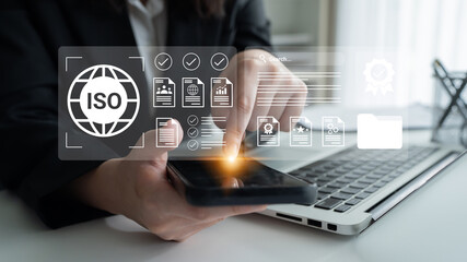 Business professional using smartphone with ISO certification icons and documents, illustrating quality management and digital transformation in workspace Gantry.