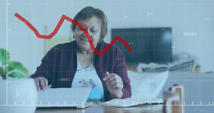 Woman noticing red finance graph appearing, placing blue sticky note while typing, tracking budget