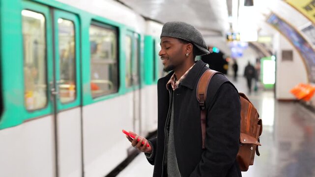 Stylish young man using smartphone while waiting for subway train
