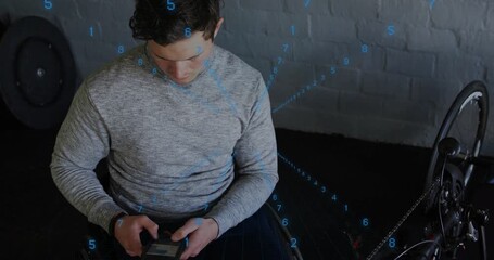 Man sitting in wheelchair using device for rehab, starting blue numeric overlay across subject