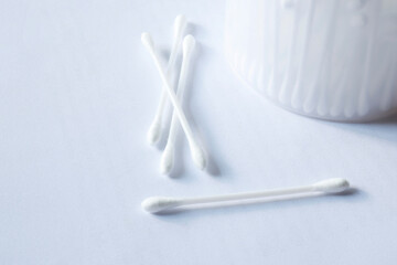 White cotton swabs on a light background with a container, ideal for themes of hygiene, healthcare, and personal care