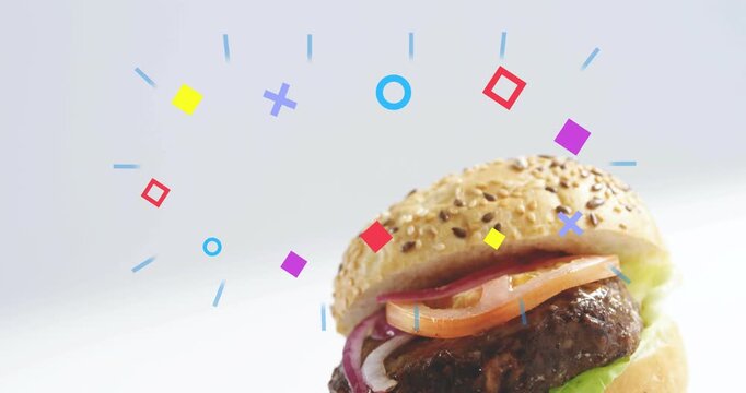 Sesame burger sliding up from lower right revealing layers while vivid shapes orbit promoting brand