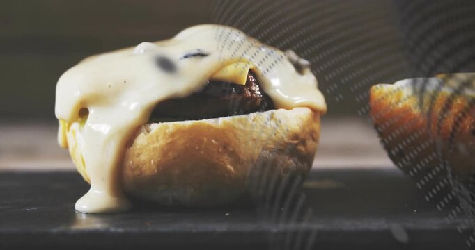Oven heat starting cheese melting, sagging drip, mesh sliding, top bun shifting revealing melt