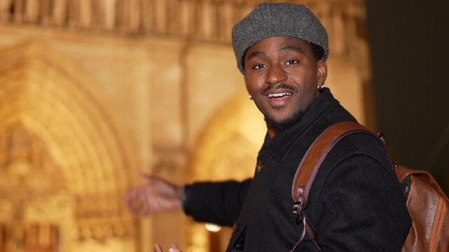 Joyful black tourist visiting notre dame in paris at night