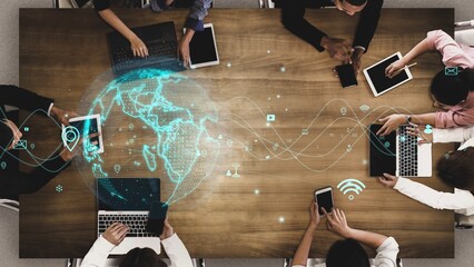 A diverse business team collaborates in a modern office setting, utilizing various digital devices for communication and strategy, highlighting global connectivity and innovation. Xenic