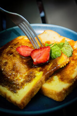 Fork Cutting Strawberry on Sweet French Toast Slices