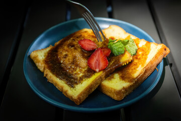 Fork Cutting Strawberry on Sweet French Toast Slices