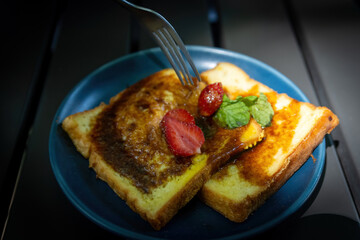 Fork Cutting Strawberry on Sweet French Toast Slices