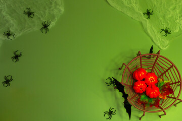 Halloween flat lay background with a frame of pumpkins, spiders, bats, illuminated by green lighting