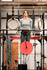 Woman performing weighted muscle up calisthenics exercise in gym