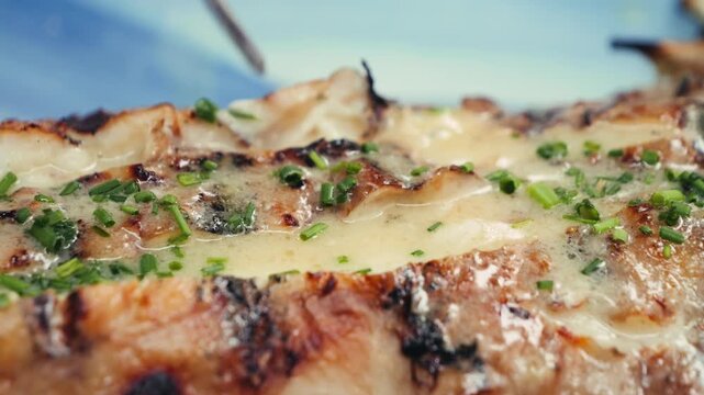 Grilled monkfish served in a restaurant with a creamy garlic sauce and greens.