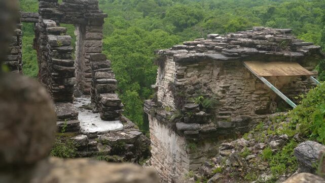 Ancient Bonampak Maya ruins rise among jungle trees with stone structures under warm daylight, establishing medium overview