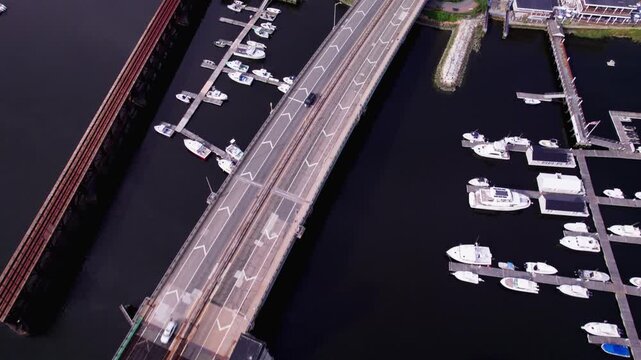 Flying over the Gillis Bridge while cars drive over it. Boats are also docked alongside the bridge across the Merrimack River.