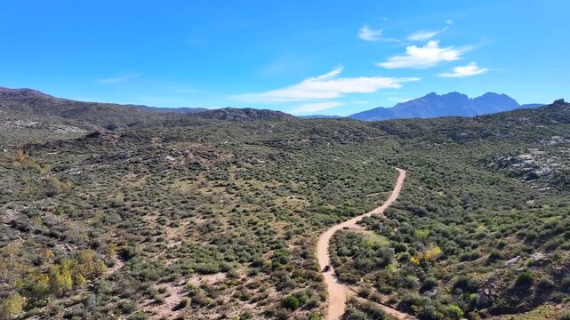 Aerial view of the rugged Four Peaks Wilderness, a landscape of contrasting greens and browns under a bright blue sky, Apache Junction, Arizona, United States.