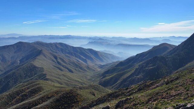 Aerial view of Four Peaks Wilderness and Tonto National Forest, with rugged mountains cloaked in muted greens and blues under a clear sky, Apache Junction, Arizona, United States.