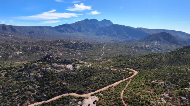 Aerial view of the rugged Four Peaks Wilderness, where the winding dirt path contrasts with the lush green vegetation, Apache Junction, Arizona, United States.