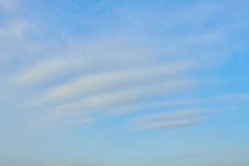 Blue sky with soft horizontal white clouds.