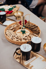 A festive DIY setup featuring yarn-wrapped ornaments on a wooden stand, surrounded by cardboard cutouts, mugs, and crafting materials on a table