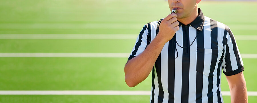 Man referee blowing a whistle on a sports green field. Concept of sports event official, fair play, and game control for athletics. Copy space background
