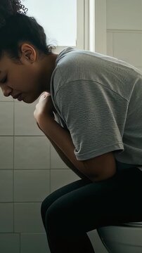 A young woman in casual clothes who is in the toilet with a stomachache (vertical video)