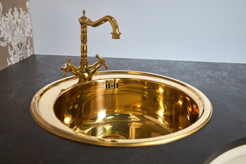 Kitchen luxurious interior with golden brass round sink basin and faucet double tap mixer in contemporary modern design with stone marble stoneware countertop.
