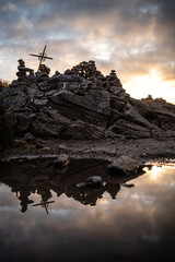 Reflet dans une flaque d'une croix et de roches au soleil couchant  © Julie