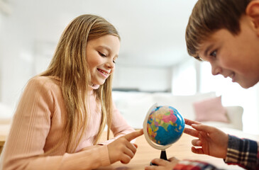 Portret of brother and sister having fun together playing with globe and learning geography and travel at home