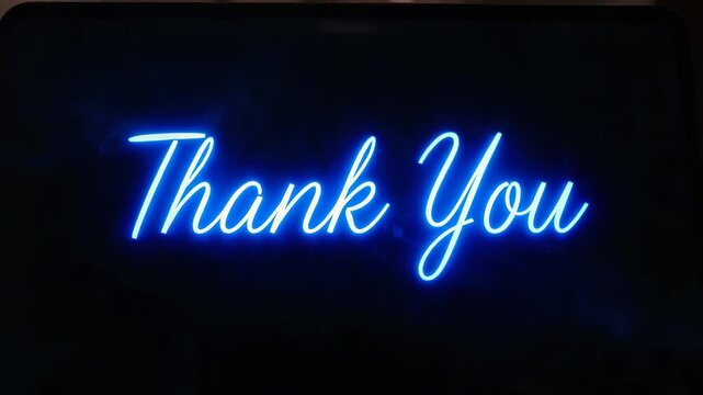 Glowing center monitor showing bright blue neon Thank You script at desk, glow flicker causing halo