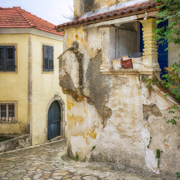 A narrow alleyway in Sinarades, an old village with authentic traditional stone buildings, a cat resting in a bucket, on the island of Corfu, Ionian Islands, Greece 