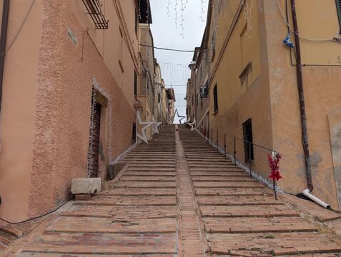vicolo nell'antico borgo medievale di Serrungarina con pavimento in mattoni in salita, circondato da edifici &egrave; decorato per le festivit&agrave; natalizie 