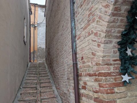 vicolo stretto lastricato con ciottoli, incorniciato da edifici in pietra antichi, nell'antico borgo medievale di Serrungarina