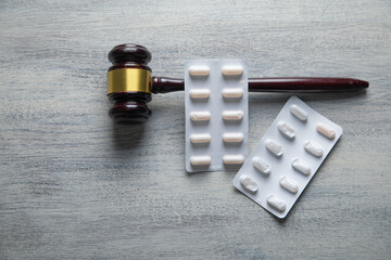 Judge gavel and medical pills on the table.