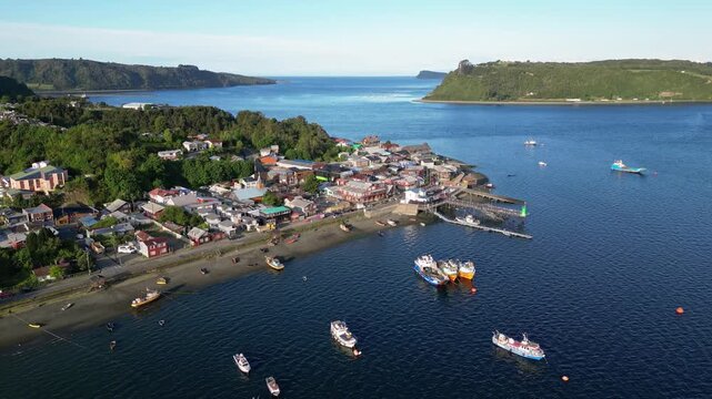 Chiloe Island, Chile: Aerial drone footage of fishing boats and trawler by the harbor and pier in the very tranquil Quemchi, Chiloe Island in Lake District of Chile. Taken with tilt up motion