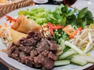 Vibrant mixed vietnamese dish with grilled beef spring rolls fresh herbs and vegetables