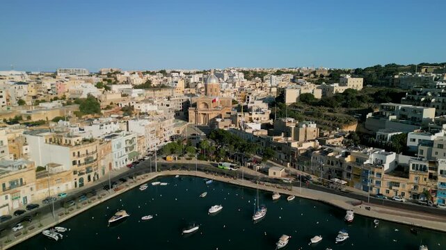 Aerial 4K 90-degree orbit shot with zoom towards St Joseph Parish Church in Kalkara, Malta