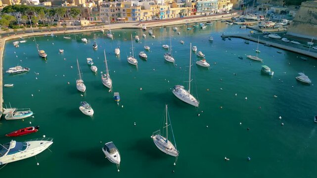 Aerial view of luxury yachts and sailboats in a crowded marina, Malta. Top down drone shot of turquoise Mediterranean water and summer nautical lifestyle.
