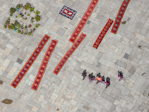 Aerial view of red carpets laid out on a stone courtyard near Gangtey Monastery, with people gathered around, Gangtey Monastery, Phobjikha valley, Bhutan.