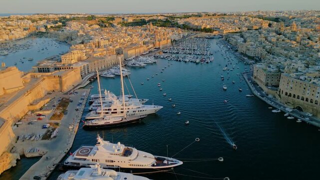 Aerial view of luxury yachts and sailboats in a crowded marina, Malta. Top down drone shot of turquoise Mediterranean water and summer nautical lifestyle.
