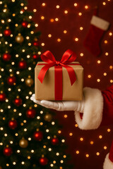Obraz premium Santa claus giving christmas present with holiday tree lights