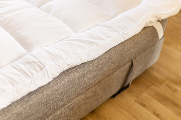 A mattress topper is on the sofa to provide extra comfort for sleeping. The scene shows a simple setup for a casual sleep space at home in the evening