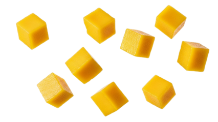 Eight bright yellow mango cubes scattered against a white background with abstract yellow and