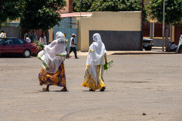 Women with white scarves and yellow dresses walking in Asmara, Eritrea