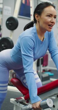 Gym workout. Back exercise. 4k footage Caucasian woman trains back with dumbbell. An intense gym workout. A determined workout as a woman performs dumbbell rows to build back strength.
