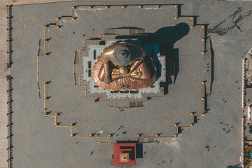 Aerial view of the Great Buddha Dordenma statue gleaming gold against the vast open plaza, an emblem of serenity and cultural grandeur, Thimphu, Bhutan.